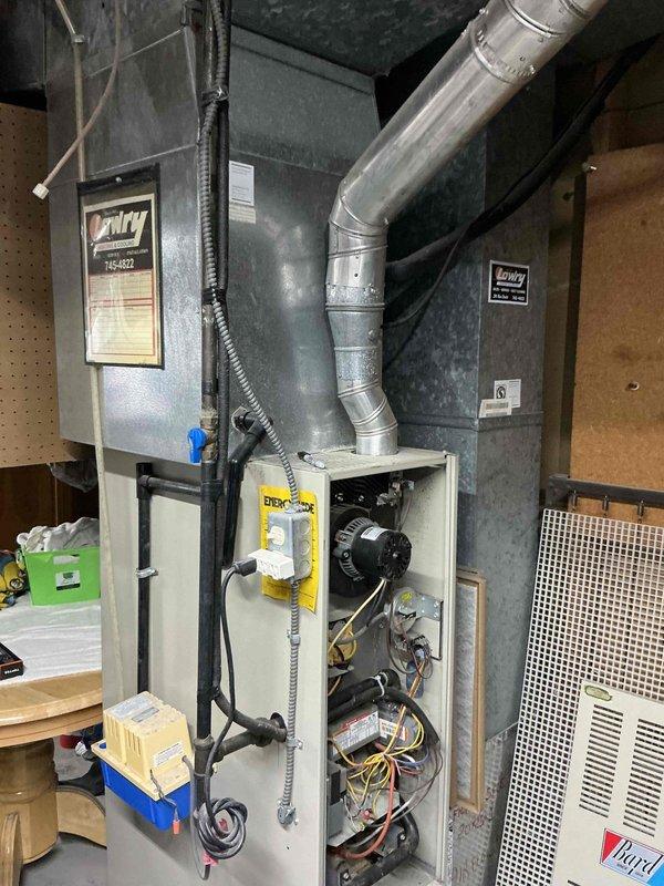 Conducted comprehensive assessment of 31-year-old residential HVAC system including furnace and air conditioning equipment located in basement utility area. Evaluated existing furnace unit with exposed blower motor assembly, electrical wiring connections, and ductwork configuration including main supply trunk line and return air system. Documented current equipment condition, installation layout, and mechanical room setup to provide detailed replacement estimate for aging system that has exceeded typical service life expectancy.