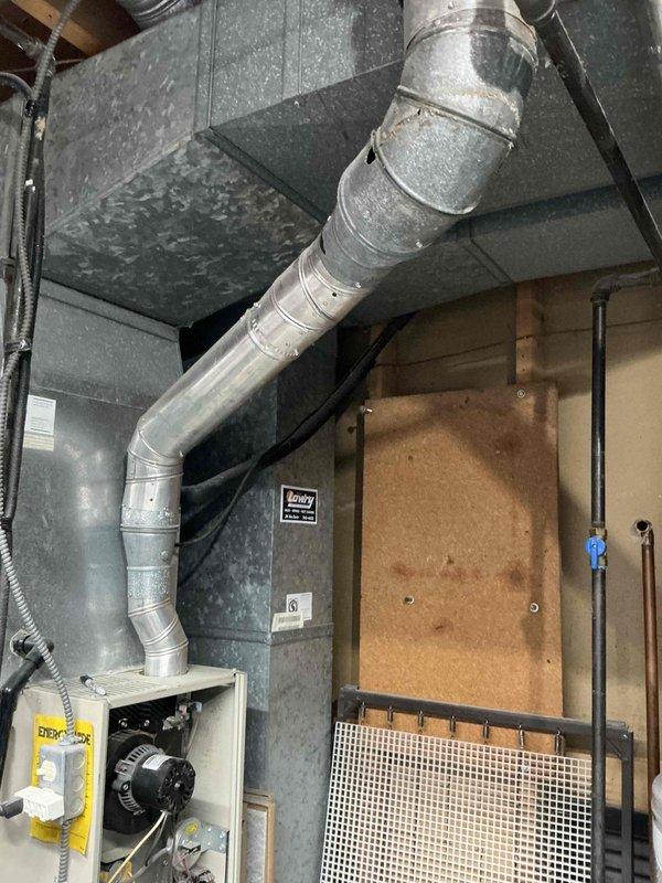 Conducted comprehensive assessment of 31-year-old residential HVAC system including furnace and air conditioning equipment located in basement utility area. Evaluated existing furnace unit with exposed blower motor assembly, electrical wiring connections, and ductwork configuration including main supply trunk line and return air system. Documented current equipment condition, installation layout, and mechanical room setup to provide detailed replacement estimate for aging system that has exceeded typical service life expectancy.