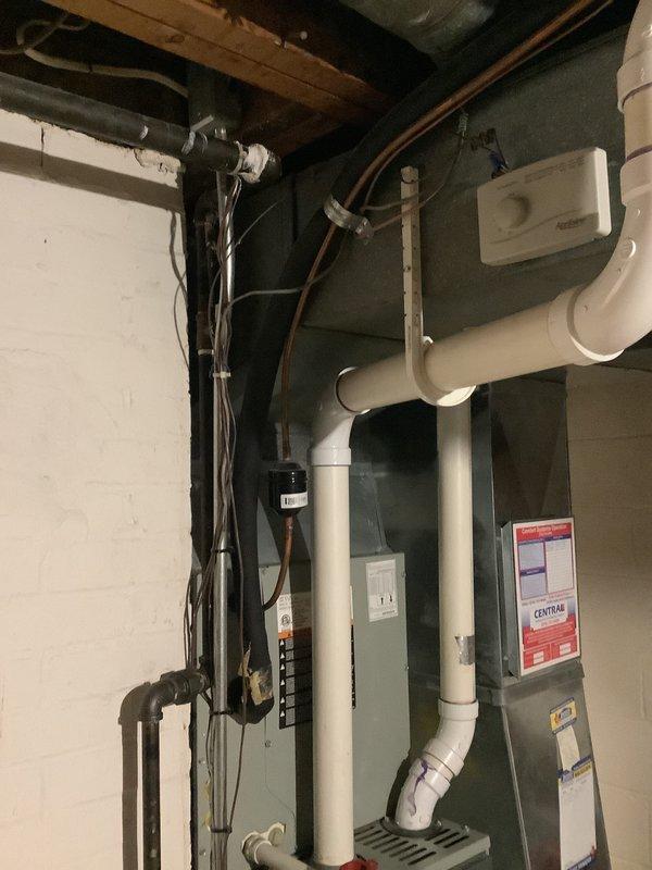 Conducted comprehensive HVAC system evaluation for furnace replacement in residential basement mechanical room. Assessed existing gray furnace unit with current ductwork configuration, including sheet metal distribution system and PVC venting arrangement. Documented equipment specifications, spatial constraints, and existing infrastructure including plumbing interfaces, electrical service, and cold air return framing to prepare detailed replacement estimate. Photographed current system layout showing vertical and horizontal duct runs, wall-mounted components, and mechanical room accessibility for future installation planning.