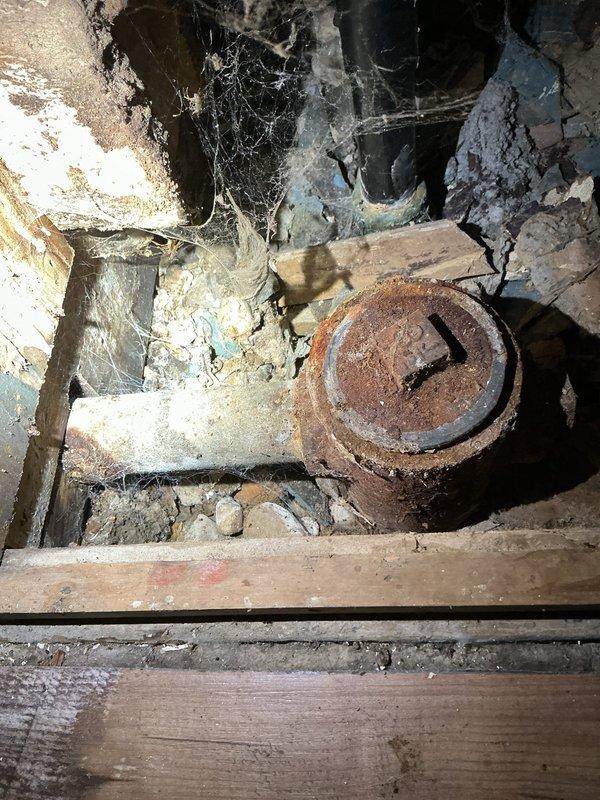 Responded to service call for clogged drain in 1950s-era home. Upon inspection, identified obsolete drum trap configuration on bathtub drain system requiring replacement. Assessed deteriorated plumbing infrastructure beneath fixture, noting severely corroded cleanout access point and compromised piping showing extensive rust and age-related degradation. Documented existing conditions including vintage tub spout and drain assembly. Provided comprehensive estimate for drum trap removal, drain line replacement, and associated fixture updates to bring system up to current plumbing standards.