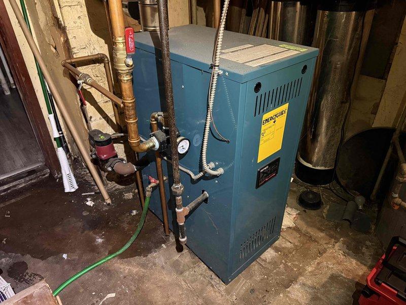 Completed routine maintenance inspection on residential boiler system for MVP customer. Performed visual assessment of teal-colored boiler unit, verified operational status of all connected components including copper piping, pressure gauge, circulator pump, and expansion tank. Documented equipment condition through photographic records showing boiler with proper ventilation, manufacturer labeling intact, and all plumbing connections secure. System found to be functioning within normal parameters with no immediate service requirements identified at time of visit.