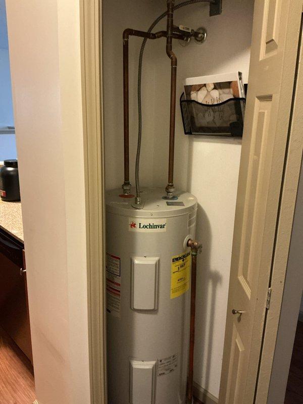 Responded to service call for non-functional natural gas water heater. Upon arrival, inspected Lochinvar residential tank-type water heater installed in interior closet space. Performed diagnostic assessment of unit including visual inspection of gas supply connections, copper water supply lines with braided flex connectors, temperature and pressure relief valve, and electrical components. Verified proper venting configuration and clearances within closet installation. Documented existing conditions with photographs showing unit specifications, energy guide labeling, access panels, and plumbing connections for service records.