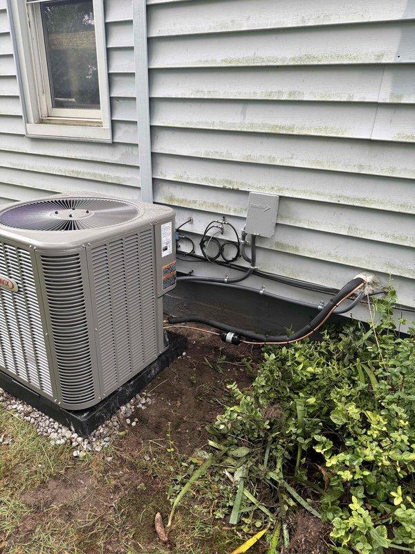 # HVAC Install - Complete System

Completed installation of a 90% efficiency furnace and air conditioning system at residential property. Installed new dark gray air handler unit in basement utility room with proper vertical positioning and clearances. Ran white PVC condensate drain lines and installed black electrical conduit to unit per code requirements. Connected unit to existing ductwork system in basement mechanical room.

Exterior work included placement of beige/tan air conditioning condenser unit on ground pad adjacent to building. Mounted gray electrical disconnect box on exterior wall with proper wiring connections. Ran copper refrigerant lines from condenser to indoor air handler, completing refrigerant circuit between components. System tested and confirmed operational with proper airflow and temperature differential across both heating and cooling modes.