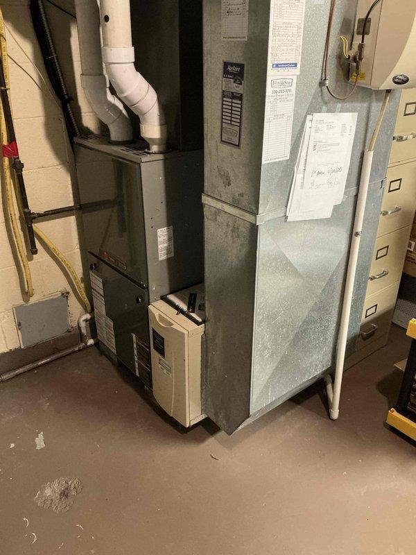 Conducted comprehensive furnace replacement estimate at residential property. Evaluated existing gray metal furnace unit in basement mechanical room, documenting current system configuration including white PVC venting, copper gas line routing, and auxiliary humidifier component. Assessed equipment age, condition, and compatibility requirements for replacement system recommendations, capturing detailed photos of existing installation for proposal development.