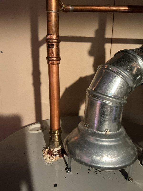 Responded to emergency water leak in basement with active water discharge from ceiling causing carpet saturation. Located source at corroded copper pipe connection near water heater, successfully shut off main water supply to stop flooding. Identified failed fitting with visible corrosion and mineral deposits requiring replacement; coordinated with restoration company for water damage remediation with follow-up appointment scheduled to complete permanent pipe repair once drying process is complete.
