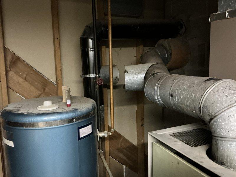 Completed estimate for replacement of 40+ year old oil furnace rated at 120,000 BTU with 10/2 electrical service at 230 volts. Unit has reached end of service life with obsolete parts no longer available for repair. Documented existing HVAC system configuration including ductwork connections, water heater proximity, and mechanical room layout for replacement planning.