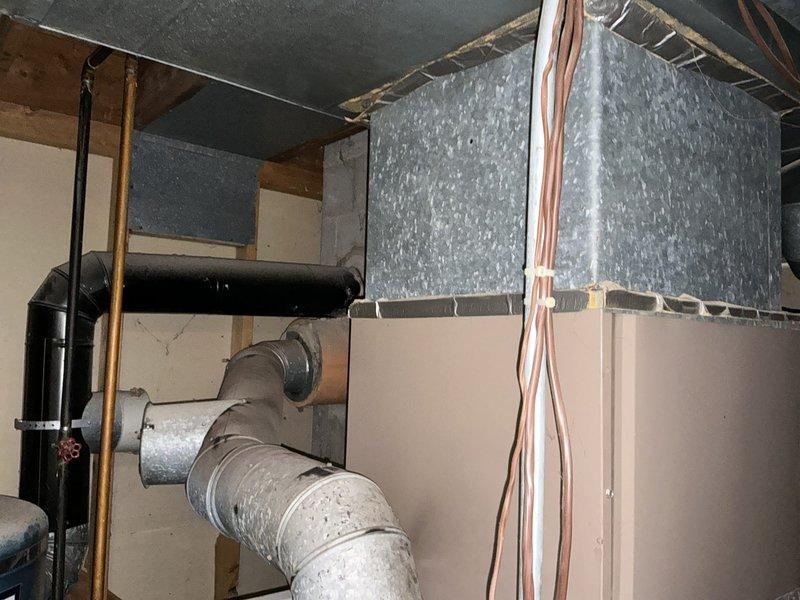Completed estimate for replacement of 40+ year old oil furnace rated at 120,000 BTU with 10/2 electrical service at 230 volts. Unit has reached end of service life with obsolete parts no longer available for repair. Documented existing HVAC system configuration including ductwork connections, water heater proximity, and mechanical room layout for replacement planning.