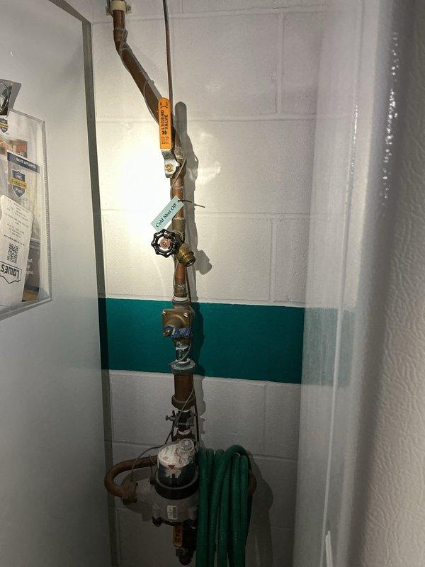 Responded to customer complaint of rattling and banging noises occurring intermittently during washing machine fill cycles and occasionally when shower is running. Upon arrival, inspected main water supply plumbing system and identified water hammer condition caused by inadequate air cushioning in the supply lines. Examined vertical copper pipe assembly including main shutoff valve, pressure regulator, and associated brass fittings for proper operation and secure mounting. Verified pressure gauge readings were within normal parameters and confirmed all compression fittings and connections were tight with no visible leaks. Assessed condition of existing plumbing infrastructure, noting aged copper piping with minor surface oxidation but structurally sound. Documented installation with photographs showing complete plumbing assembly, pressure regulation equipment, and valve configuration for service records.