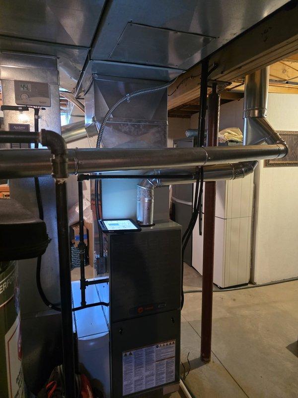 Completed MVP furnace maintenance in basement utility area. Performed comprehensive inspection of dark-colored furnace unit, including examination of heat exchanger, burner assembly, and all mechanical components. Verified proper operation of blower motor and checked all electrical connections for safety and functionality. Inspected metal ductwork system throughout the space, including horizontal supply ducts, flexible connectors, and rigid metal sections routed through ceiling joists. Confirmed all duct connections were secure and properly sealed. Tested furnace ignition sequence and verified proper flame characteristics. System operating within manufacturer specifications upon completion of maintenance service.