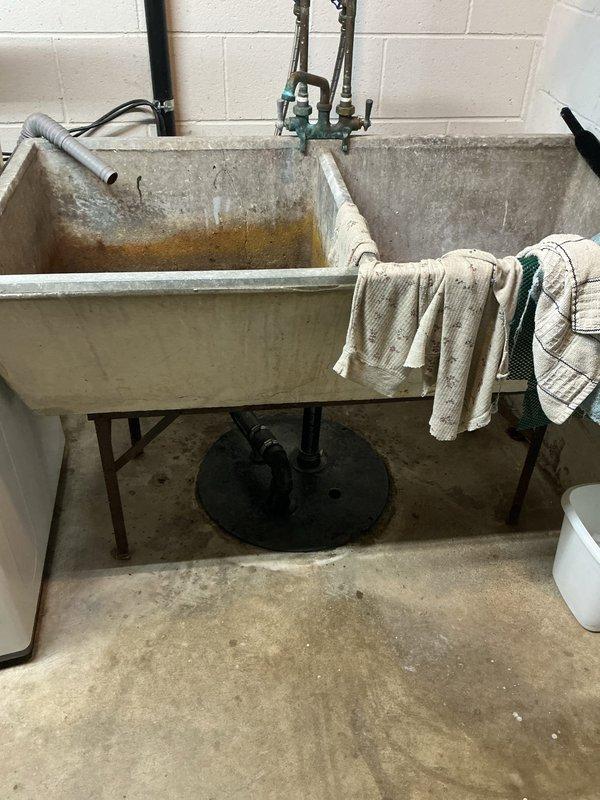 Responded to service call for malfunctioning sump pump system. Upon arrival, conducted thorough inspection of basement utility area and sump pump installation. Assessed pump functionality, discharge lines, and float switch operation. Documented existing conditions of utility sink and surrounding plumbing infrastructure through photographic evidence showing aged concrete fixtures, mineral deposits, and water staining patterns indicative of long-term usage. Completed diagnostic evaluation and provided recommendations for pump replacement or repair to ensure proper basement water management and prevent potential flooding issues.