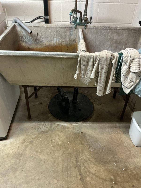Responded to service call for malfunctioning sump pump system. Upon arrival, conducted thorough inspection of basement utility area and sump pump installation. Assessed pump functionality, discharge lines, and float switch operation. Documented existing conditions of utility sink and surrounding plumbing infrastructure through photographic evidence showing aged concrete fixtures, mineral deposits, and water staining patterns indicative of long-term usage. Completed diagnostic evaluation and provided recommendations for pump replacement or repair to ensure proper basement water management and prevent potential flooding issues.