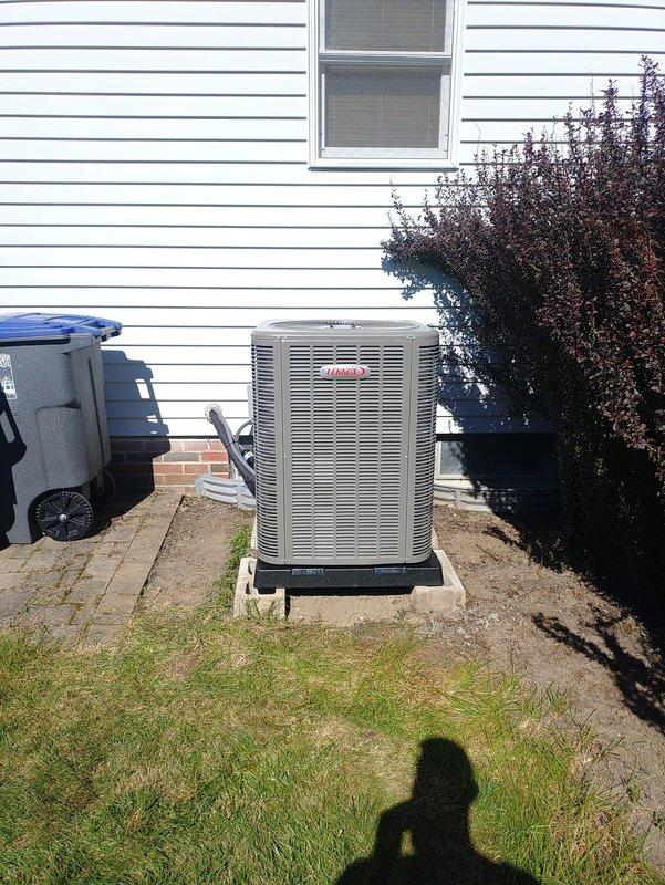 Completed full HVAC system installation including new 90% efficiency air conditioning unit positioned on concrete pad against residential exterior with proper clearances maintained. Replaced faulty 30-amp Littelfuse RNR fuses that showed heat discoloration and oxidation from previous system operation. New outdoor condenser unit installed on black composite platform with proper leveling, connected to electrical service with new fusing, and system commissioned with successful startup and operational testing.