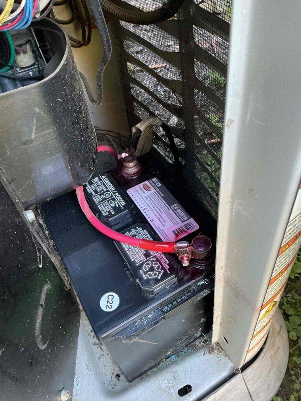 Completed routine preventative maintenance on residential Generac standby generator unit located outside near garage. Inspected and serviced dual battery system, verifying proper terminal connections and cable integrity. Documented battery compartment condition showing normal weathering and minor dust accumulation consistent with outdoor installation, with all electrical connections secure and functional.