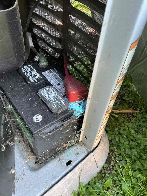 Completed routine preventative maintenance on residential Generac standby generator unit located outside near garage. Inspected and serviced dual battery system, verifying proper terminal connections and cable integrity. Documented battery compartment condition showing normal weathering and minor dust accumulation consistent with outdoor installation, with all electrical connections secure and functional.