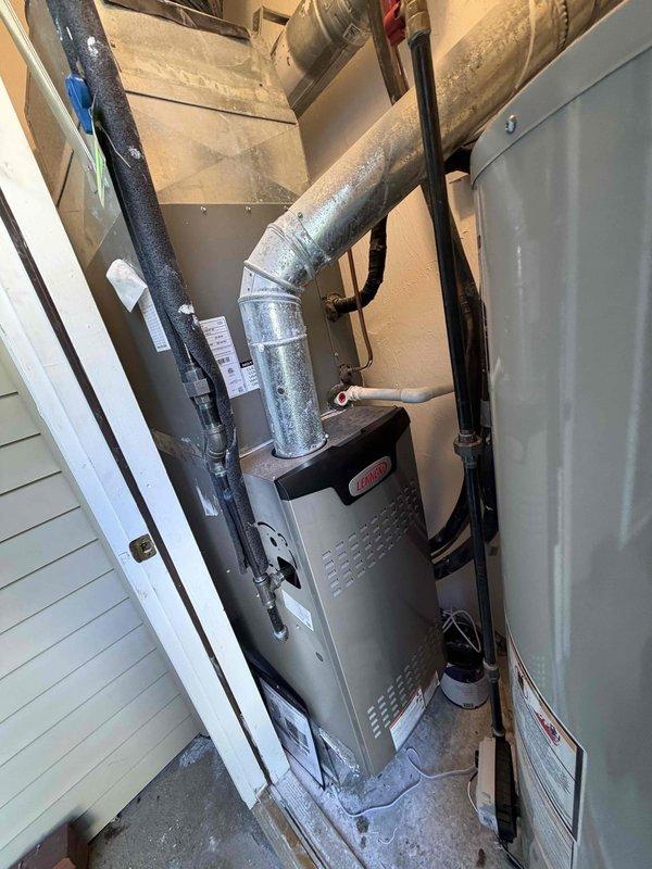 Completed installation of 80% AFUE high-efficiency gas furnace in residential utility closet. Unit installed with proper clearances, metallic supply ductwork connected to existing distribution system, and black PVC condensate drain piping routed with appropriate traps and termination. All electrical connections, gas line hookup, and combustion air provisions completed per manufacturer specifications and local code requirements.