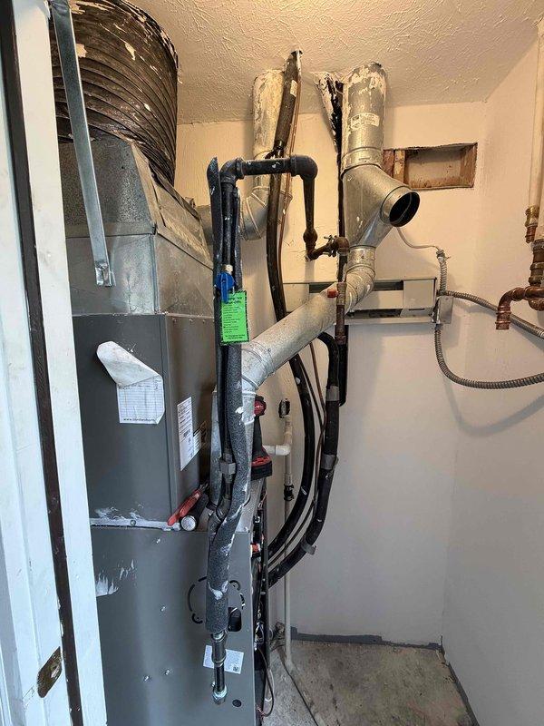 Completed installation of 80% AFUE high-efficiency gas furnace in residential utility closet. Unit installed with proper clearances, metallic supply ductwork connected to existing distribution system, and black PVC condensate drain piping routed with appropriate traps and termination. All electrical connections, gas line hookup, and combustion air provisions completed per manufacturer specifications and local code requirements.
