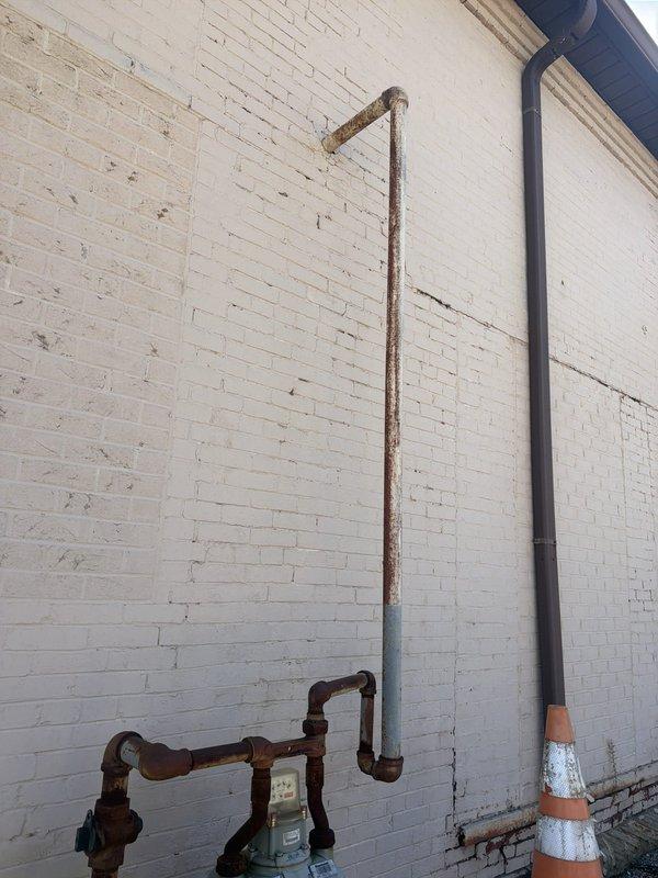 Performed site assessment and provided estimate for installation of natural gas line to power standby generator. Evaluated existing gas meter location and determined optimal routing path from meter assembly to proposed generator placement area. Documented current gas infrastructure including aged copper piping with visible corrosion and patina, existing meter connections, and protective bollards. Assessed wall penetration requirements through white brick exterior and measured distances for material calculations. Generator unit to be supplied by property owner. Provided comprehensive estimate covering gas line installation, required fittings, pressure testing, and connection specifications per local code requirements.