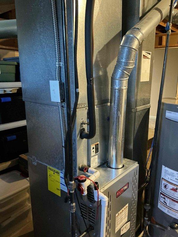 Conducted comprehensive replacement estimate for 22-year-old residential air conditioning system. Evaluated existing HVAC infrastructure in basement utility area, including vertical air handler unit, associated ductwork, and RUUD brand equipment. Documented current system configuration with detailed photographs showing air handler placement, metallic exhaust venting, water heater proximity, and existing duct runs to provide accurate replacement specifications and equipment recommendations.