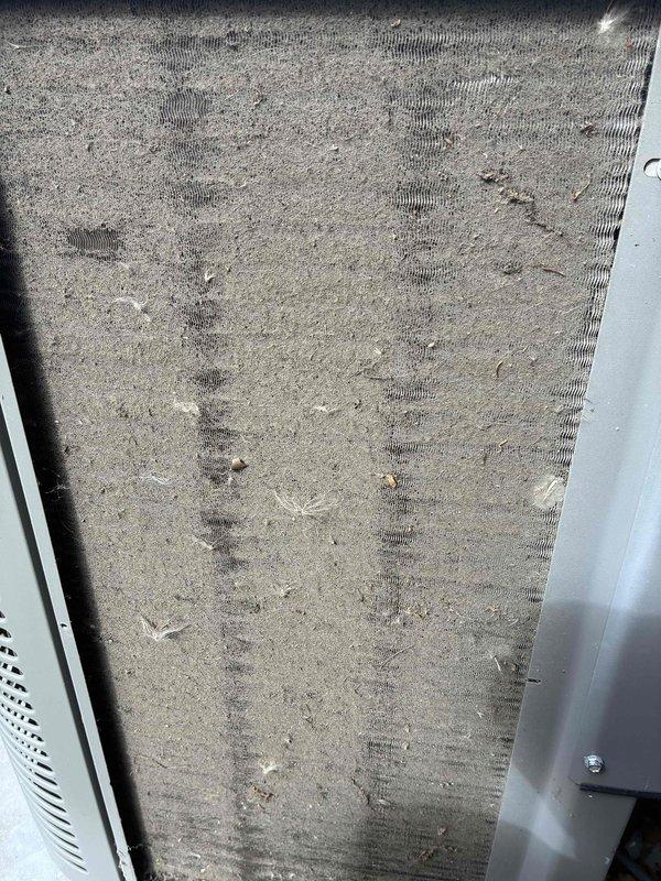 Completed scheduled MVP cooling maintenance visit on residential air conditioning system. Inspected outdoor condenser unit and found finned coil surface with moderate accumulation of dirt, dust, and debris between fins, along with minor fin damage typical of outdoor exposure. Examined air filter and discovered heavy soiling with significant dust and debris buildup requiring attention. Documented equipment condition through photographs showing condenser coil deterioration and filter contamination levels. System components assessed for operational efficiency and maintenance requirements per recurring service protocol.