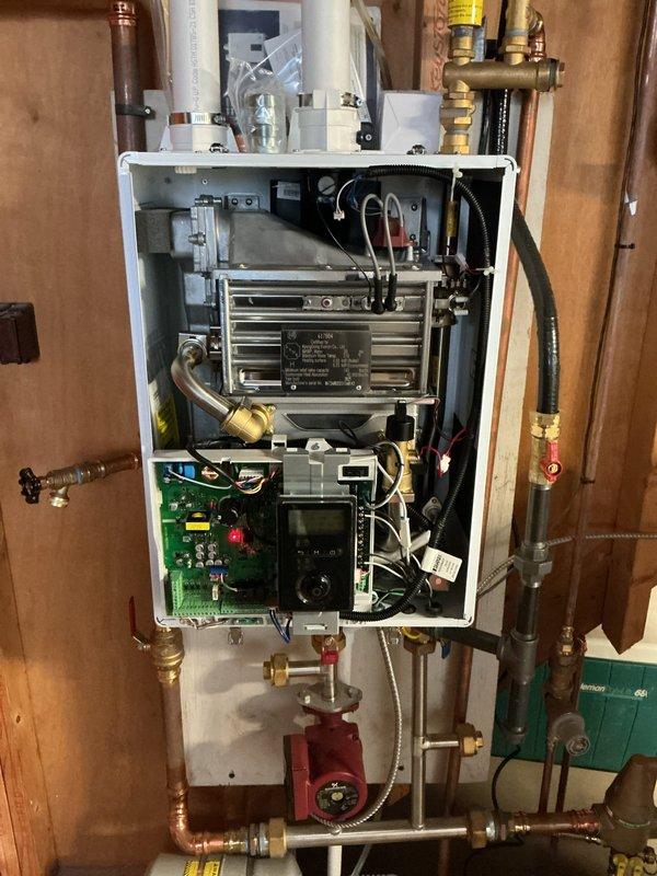 # Boiler Repair - Troubleshooting and Diagnostics

Responded to service call for 9-year-old wall-mounted boiler experiencing error codes, low system pressure, and intermittent shutdowns. Upon arrival, removed front access panel to inspect internal components including heat exchanger, control board, circulation pump, and hydronic piping connections. 

Performed visual inspection of green control board for burnt components or loose connections. Checked digital display for active error codes and system status indicators. Examined heat exchanger fins for corrosion or blockage. Inspected red circulation pump for proper operation and verified electrical connections to pump motor.

Evaluated system pressure using onboard gauges and checked all visible piping connections, brass fittings, and shut-off valves for leaks or air infiltration points. Tested pressure relief valve operation and examined expansion tank connection. Documented all visible components including copper piping, flexible conn