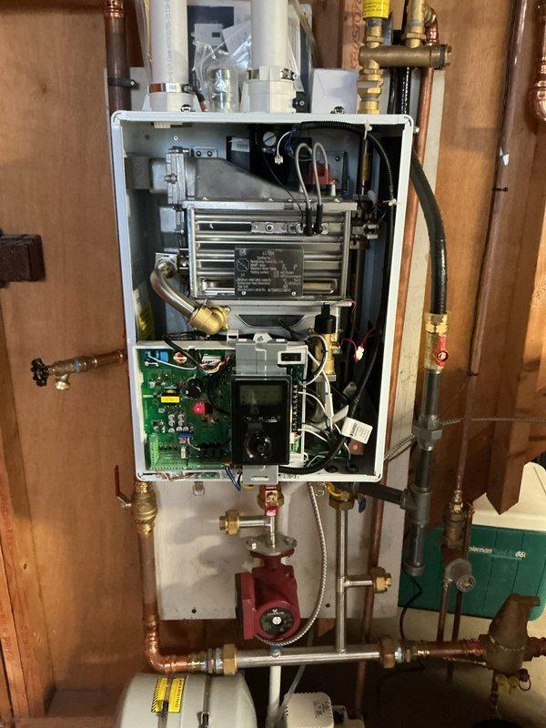 # Boiler Repair - Troubleshooting and Diagnostics

Responded to service call for 9-year-old wall-mounted boiler experiencing error codes, low system pressure, and intermittent shutdowns. Upon arrival, removed front access panel to inspect internal components including heat exchanger, control board, circulation pump, and hydronic piping connections. 

Performed visual inspection of green control board for burnt components or loose connections. Checked digital display for active error codes and system status indicators. Examined heat exchanger fins for corrosion or blockage. Inspected red circulation pump for proper operation and verified electrical connections to pump motor.

Evaluated system pressure using onboard gauges and checked all visible piping connections, brass fittings, and shut-off valves for leaks or air infiltration points. Tested pressure relief valve operation and examined expansion tank connection. Documented all visible components including copper piping, flexible conn
