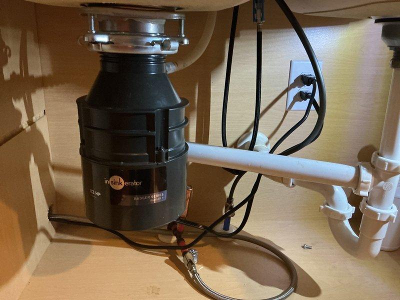 Responded to service call for garbage disposal evaluation and replacement. Upon inspection, assessed existing InSinkErator disposal unit mounted beneath kitchen sink. Evaluated disposal condition, mounting assembly, and associated plumbing connections including PVC drainage piping and electrical wiring. Completed disposal replacement, ensuring proper mounting flange installation, secure drainage connections, and electrical hookup. Verified unit operation and tested for proper drainage flow. Left work area clean with disposal functioning properly.