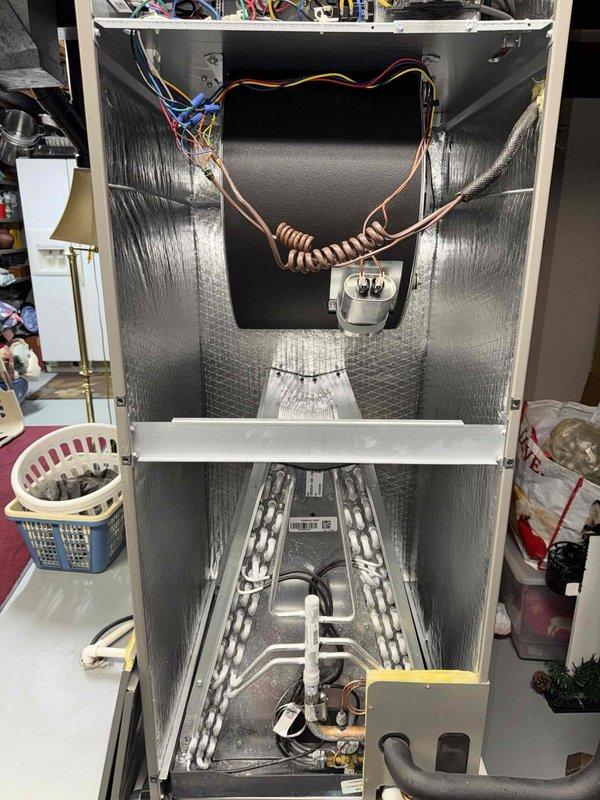Completed comprehensive MVP heating maintenance on residential air handler unit. Performed thorough inspection of evaporator coil assembly, verified A-frame coil configuration showing clean aluminum fins and copper tubing in proper condition. Examined refrigerant lines including copper coiled loop with insulation, confirmed all connections secure with no visible leaks or damage. Inspected condensate drain pan and drainage system, verified proper flow and positioning. Evaluated electrical control panel and circuit breaker configuration, checked all wire connections including high and low voltage circuits with yellow, red, blue, and black conductors properly terminated. Confirmed all wire nuts and connectors secure, verified electrical junction box and control module functioning correctly. Inspected interior cabinet insulation and structural components, all found in acceptable working condition. Unit operational and ready for heating season.