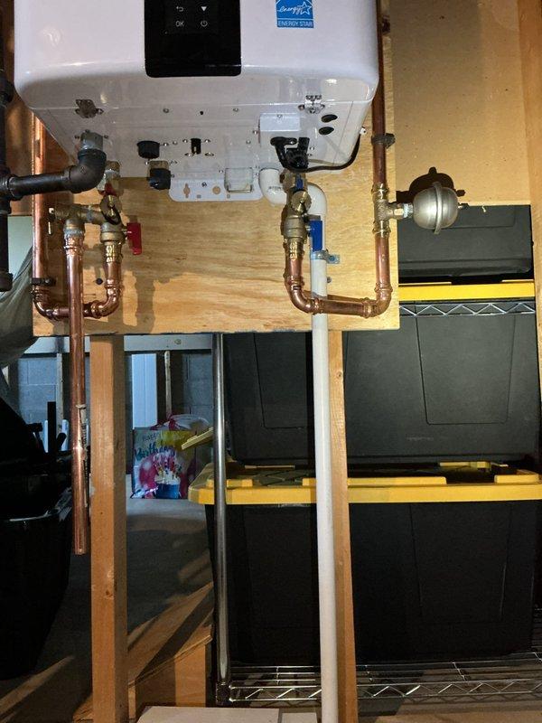 Responded to warranty callback for Navien NPE240A2 tankless water heater experiencing leak immediately following installation. Upon arrival, inspected unit mounted in basement utility area and identified water pooling on concrete floor beneath installation. Thoroughly examined all copper pipe connections, inlet/outlet fittings, and brass shut-off valves for signs of leakage. Tightened connection at inlet valve where minor seepage was detected. Pressure tested system and verified all connections were secure with no further moisture present. Cycled unit through multiple heating cycles to confirm proper operation and seal integrity. Documented installation with photographs showing unit mounting, plumbing connections, and floor conditions before departure. System operating within manufacturer specifications with no active leaks detected upon completion.