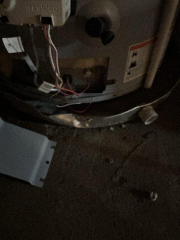 Responded to service call for tanked water heater malfunction in basement location. Upon arrival, performed comprehensive diagnostic inspection of the unit and associated plumbing connections. Examined the water heater's electrical components, including the Honeywell thermostat control and terminal connections with visible red and white wiring. Inspected flexible supply lines, rigid piping, valves, and fittings in the confined installation space. Assessed the unit's physical condition, noting the floor surface beneath showed signs of moisture exposure. Verified all connections were secure and evaluated the safety warning labels and manufacturer specifications. Completed necessary repairs to restore proper operation and functionality of the water heating system.