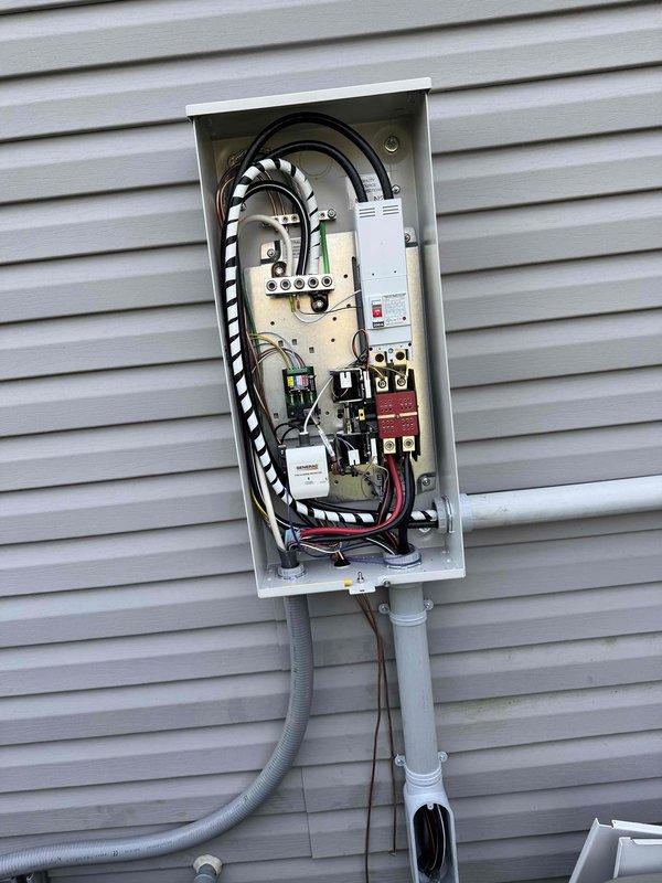 Completed installation of 22KW standby generator with 200-amp automatic transfer switch on exterior wall of residence. Ran 20 feet of gas line from existing service point to generator location, coordinated with separate contractor for gas line installation. Installed 15 feet of electrical conduit and wiring from main service panel to new exterior transfer switch panel, mounted all equipment on vinyl siding per manufacturer specifications. Configured automatic transfer switch with proper circuit breaker protection, established all electrical connections to generator unit including control wiring and power cables. Tested system operation including automatic start sequence, transfer switch functionality, and verified proper voltage output under load. All work completed to code requirements with generator positioned for adequate ventilation and service access.
