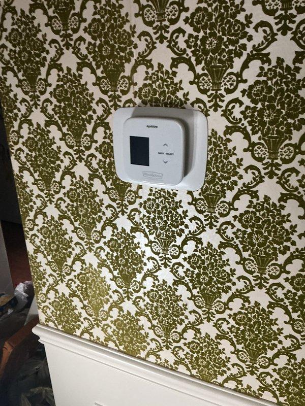 Responded to service call for erratic thermostat displaying incorrect temperature readings (fluctuating between 14°F and 82°F while actual room temperature was 60-80°F). Upon inspection, diagnosed 10-year-old Emerson thermostat with faulty temperature sensor and failing display circuit board. Removed malfunctioning thermostat from wall, documented internal components showing deteriorated circuit board connections and compromised sensor calibration. Replaced defective thermostat with new unit, verified proper wiring connections, and tested system operation to confirm accurate temperature readings and proper HVAC system communication.