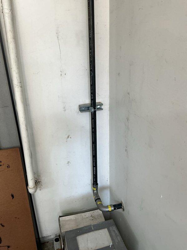 Responded to failed inspection requiring code compliance corrections for gas line installation. Installed proper metal mounting straps and brackets to secure black gas piping running vertically along interior wall, ensuring adequate support per local code requirements. Added necessary clamp-style brackets at appropriate intervals to eliminate unsupported spans. Gas line routing includes vertical run with 90-degree bend transitioning to horizontal connection at utility box. All mounting hardware properly fastened to wall structure to prevent pipe movement and maintain system integrity.