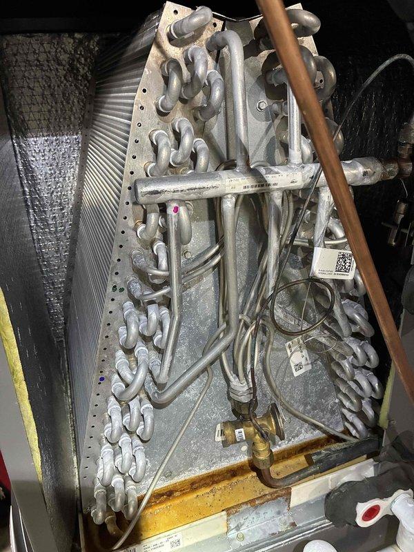 Performed a comprehensive heating maintenance inspection on a Lennox gas furnace with Aprilaire air handler, verifying condensate drain piping and neutralizer operation and checking flue venting and electrical connections. Inspected the evaporator coil assembly and found frost/mineral buildup on the coil and tubing along with heavy rust-colored staining in the drain pan, and recommended cleaning and further evaluation to ensure proper airflow and drainage.