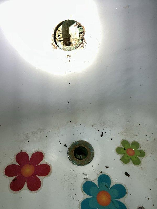 Cleared a clogged bathtub drain and addressed the broken overflow pipe, which had separated from the tub assembly. Access openings were made in the ceiling below to reach the drain and overflow piping, where heavy corrosion, mineral buildup, and deteriorated framing were found around the connections. The drain and overflow assembly was serviced to restore proper drainage, and the corroded condition of the drain ring and pipe stub was documented for the customer's awareness.
