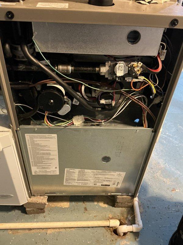 Performed recurring cooling maintenance, inspecting the furnace's internal components including the gas valve assembly, inducer motor, and wiring harness with the upper access panel removed. Replaced the pleated air filter and checked the condensate drain line, noting rust staining around the floor drain and PVC piping that may indicate past moisture or drainage issues and should be monitored.