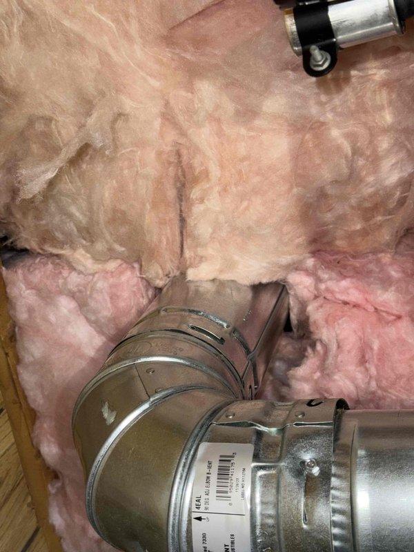 Performed a fire-safety inspection of the garage Reznor unit heater following recent attic insulation work, checking the heater, gas piping and shutoff, flexible vent connection, and galvanized flue/vent pipe for proximity to combustibles. Observed fiberglass batt insulation with torn or sagging kraft facing in the surrounding ceiling cavity and loose, displaced insulation near the vent elbow, and documented all conditions with photos.