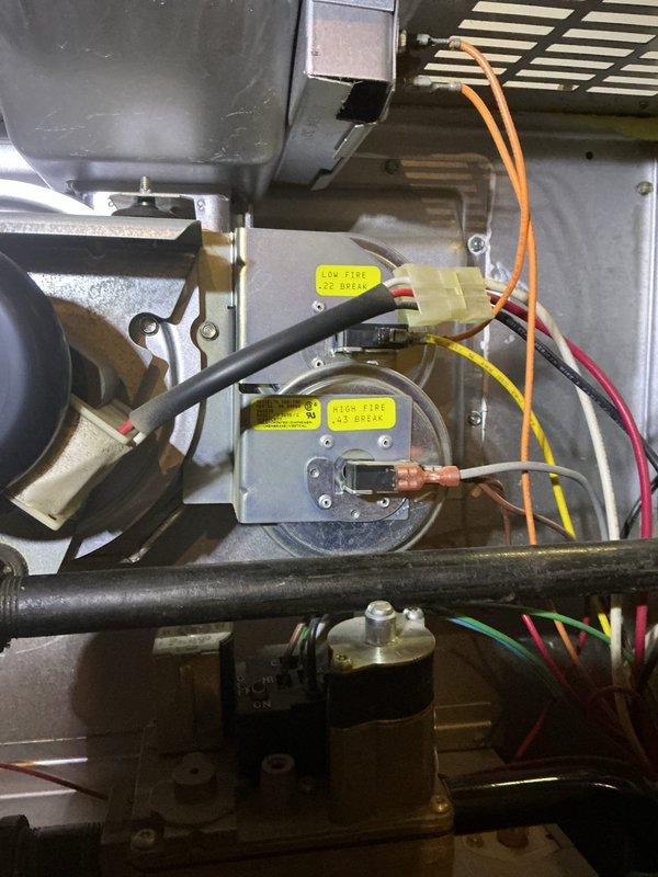 Performed a tune-up on a 28-year-old gas furnace, inspecting the burner assembly, gas valve, manifold, and gas piping, with burners exhibiting a normal blue flame pattern. Verified the low-fire and high-fire pressure switches and associated wiring connections were intact and in serviceable condition, with only light dust and wear observed and no signs of rust, frost, or component damage. Confirmed safety labels and operating instructions were present and the unit was functioning properly at completion.