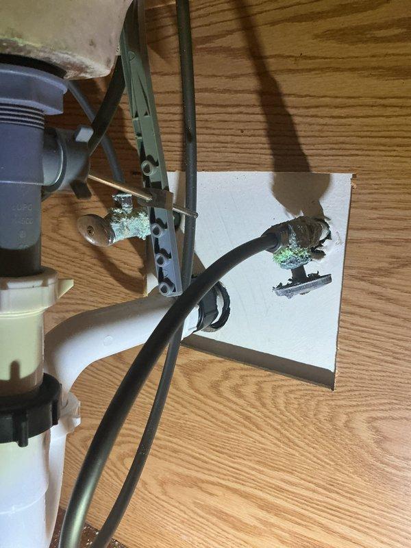 Installed customer-supplied bathroom sink faucet, connecting new braided stainless steel supply lines to the existing chrome quarter-turn angle stop valves and verifying proper operation and leak-free connections. Noted corrosion and mineral buildup on the shutoff valves and fittings beneath the sink, which should be monitored and may require valve replacement in the future.