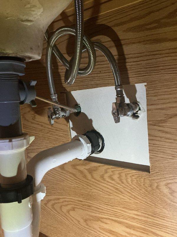 Installed customer-supplied bathroom sink faucet, connecting new braided stainless steel supply lines to the existing chrome quarter-turn angle stop valves and verifying proper operation and leak-free connections. Noted corrosion and mineral buildup on the shutoff valves and fittings beneath the sink, which should be monitored and may require valve replacement in the future.