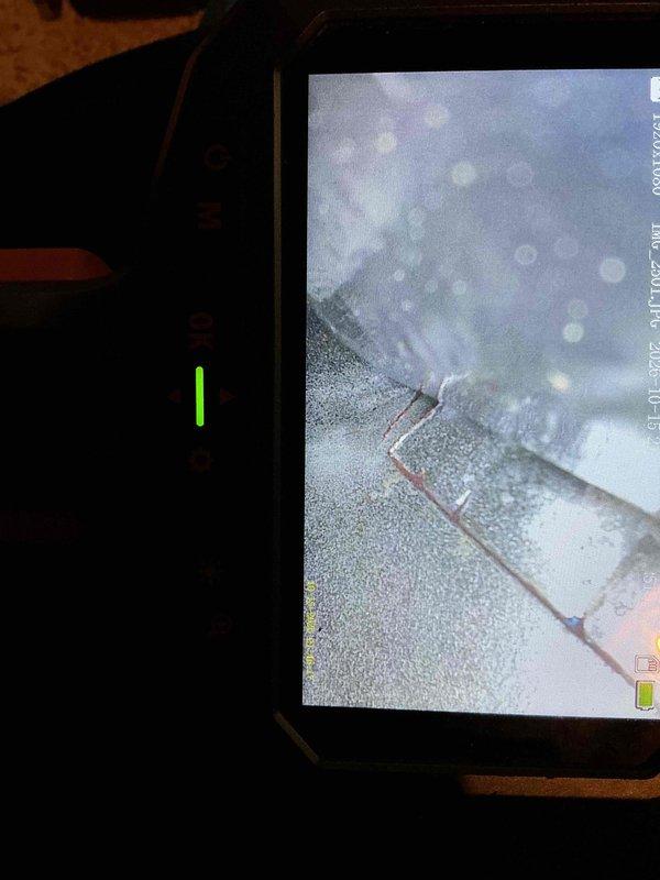 Performed a furnace inspection in response to a reported cracked heat exchanger, using a borescope to visually examine the heat exchanger and surrounding internal surfaces. Imaging showed a visible seam and gap with surface corrosion and discoloration on the sheet metal, and repairs are recommended before maintenance can be performed.