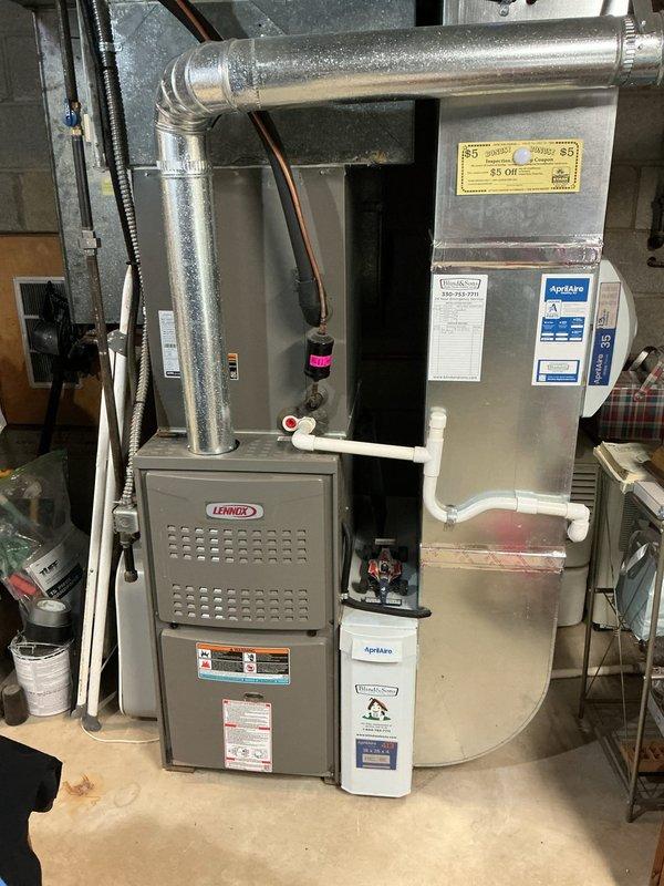 Performed a cooling maintenance inspection on the residential split system, including the outdoor Lennox condenser unit, which was found clear of debris with no visible damage, and the indoor Lennox furnace/air handler installation. Inspected the condensate drain piping and valve, refrigerant line set and insulation, flue connection, and the AprilAire humidifier and filter housing, with no signs of rust, frost, ice buildup, or leakage observed. The system was verified to be in good operating condition.