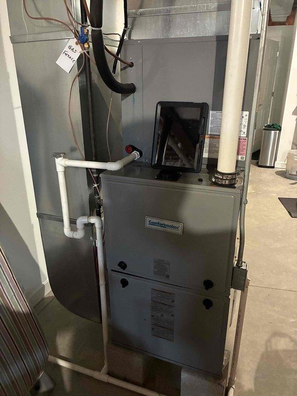 Performed a seasonal tune-up on a Comfortmaker gas furnace, including inspection of the blower assembly, which showed light dust buildup on the squirrel-cage wheel blades with no cracks, rust, or ice. Verified the PVC venting and condensate drain piping were intact and free of visible damage, and confirmed the unit and surrounding area were clean with no signs of corrosion or leaks. Furnace was left in good working condition.