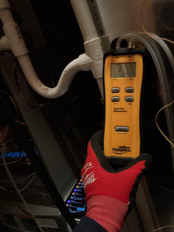 Performed recurring heating maintenance, inspecting the pleated air filter and finding it clean and in serviceable condition with no tearing or heavy debris loading. Measured system static pressure using a dual-port digital manometer to verify airflow performance, and noted staining on the condensate PVC piping for continued monitoring.