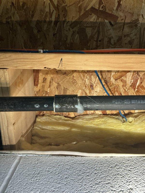 Performed leak detection on the interior gas piping using bubble solution and located an active leak at a threaded coupling on the black iron gas line in the basement joist cavity, with surface corrosion and pitting noted on the adjacent pipe. The affected section was identified for repair, and the remaining accessible gas piping, including the elbow and union fittings, was inspected for additional leaks.