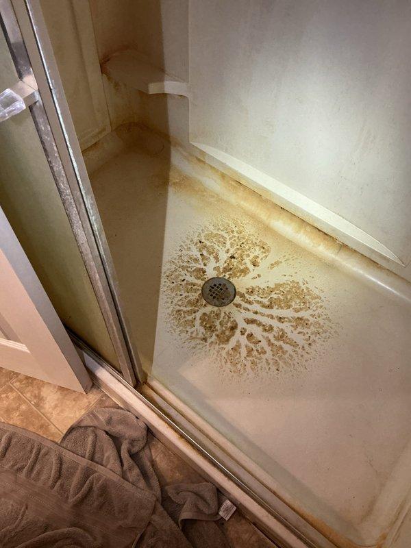 Responded to a backed-up, overflowing basement bathroom toilet and cleared the main blockage using drain-clearing equipment, restoring proper flow through the toilet and connected drain line. Flushed the line to confirm full drainage, then cleaned and sanitized the affected floor area around the fixture. Residual staining at the shower drain and pan was noted as mineral and rust buildup, and the system was verified free-flowing with no remaining backup.