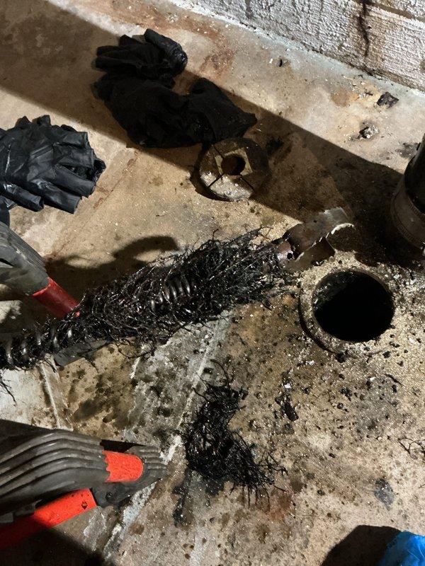 Removed the cleanout cap and pumped down the main drain line to clear standing wastewater, then cleared the blockage with a drain cleaning machine, retrieving a heavy mass of sludge, hair-like debris, and root-type fibrous material from the line. The main drain is now flowing freely, restoring use of the facilities.