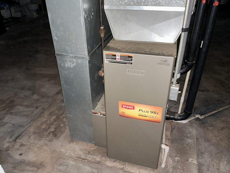 Performed a furnace replacement estimate in a basement affected by recent water intrusion, inspecting the existing Bryant Plus 95s Evolution Series 95% AFUE upright gas furnace, its galvanized plenum and ductwork, condensate and PVC drain lines, gas and refrigerant piping, and electrical connections. Documented the unit's condition, including surface staining, wear, and dust accumulation, and noted that the unit's proximity to the floor and the water exposure require evaluation for possible damage before proceeding with replacement recommendations.