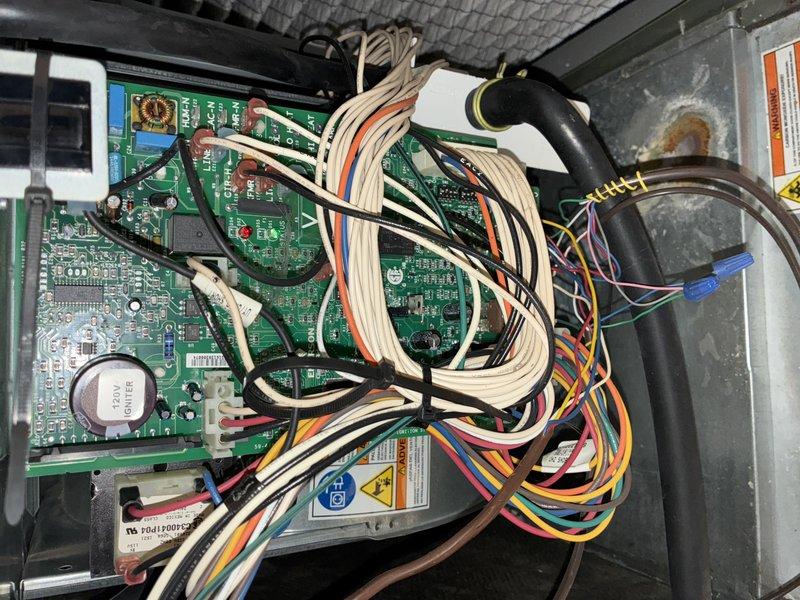 Performed scheduled heating maintenance on a 10-year-old furnace, inspecting the control board, wiring harness, and connections and noting surface corrosion on the cabinet wall. Inspected the blower assembly and found heavy dust accumulation on the blower wheel blades and a foreign object lodged between the blades, indicating the wheel requires cleaning to restore proper airflow and system efficiency.