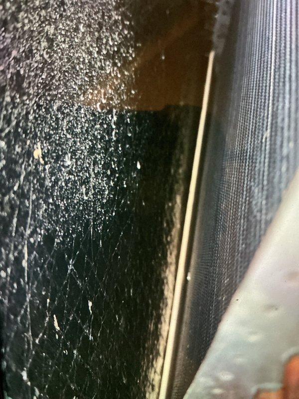 Performed seasonal maintenance on a 20-year-old furnace, inspecting the air handler cabinet and noting granular debris buildup and fine cracking on the insulated surfaces, along with the evaporator coil condition. Inspected the whole-house humidifier, its PVC drain line, and the flexible duct connection, noting moisture on the duct surface, and verified the gas line, electrical disconnect, and wiring were intact. Recommend monitoring the insulation degradation and moisture conditions, and evaluating the aging system for future replacement.