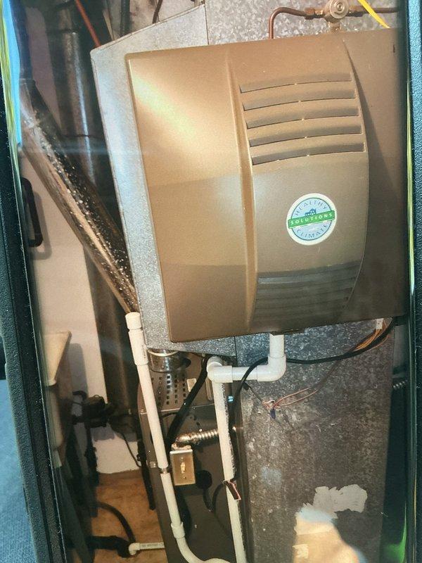 Performed seasonal maintenance on a 20-year-old furnace, inspecting the air handler cabinet and noting granular debris buildup and fine cracking on the insulated surfaces, along with the evaporator coil condition. Inspected the whole-house humidifier, its PVC drain line, and the flexible duct connection, noting moisture on the duct surface, and verified the gas line, electrical disconnect, and wiring were intact. Recommend monitoring the insulation degradation and moisture conditions, and evaluating the aging system for future replacement.